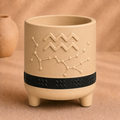 Warm beige Aquarius zodiac planter with raised Aquarius symbol, constellation, black zodiac band and footed base