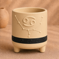Warm beige Cancer zodiac planter with raised Cancer symbol, constellation, black zodiac band and footed base
