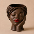 Nia Afrocentric face planter with sculpted braids, resting hand, and red lips