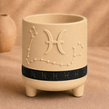 Warm beige Pisces zodiac planter with raised Pisces symbol, constellation, black zodiac band and footed base