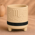 Warm beige Scorpio zodiac planter with raised Scorpio symbol, constellation, black zodiac band and footed base